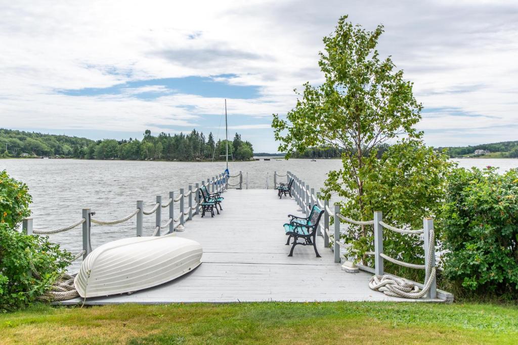 a dock with a boat and chairs on the water at OCEAN BAY VIEW Luxury Guesthouse in Musquodoboit Harbour