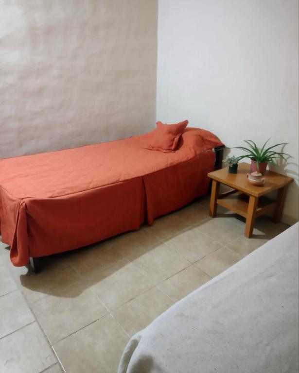 1 dormitorio con cama roja y mesa en Hospedaje Los Girasoles en Salto de las Rosas