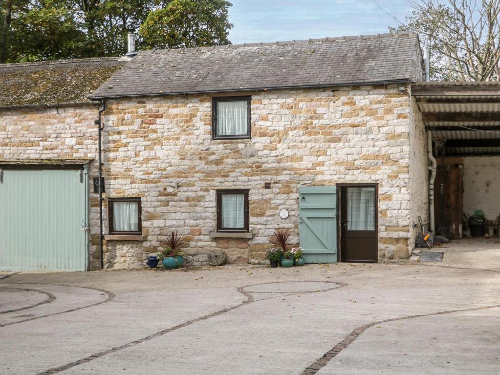 a brick house with two garage doors and a driveway at Harry Eyre Cottage in Castleton