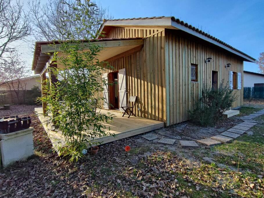 un petit hangar avec une terrasse couverte et une chaise dans la cour dans l'établissement Chalet calme 3 ch, à Sanguinet