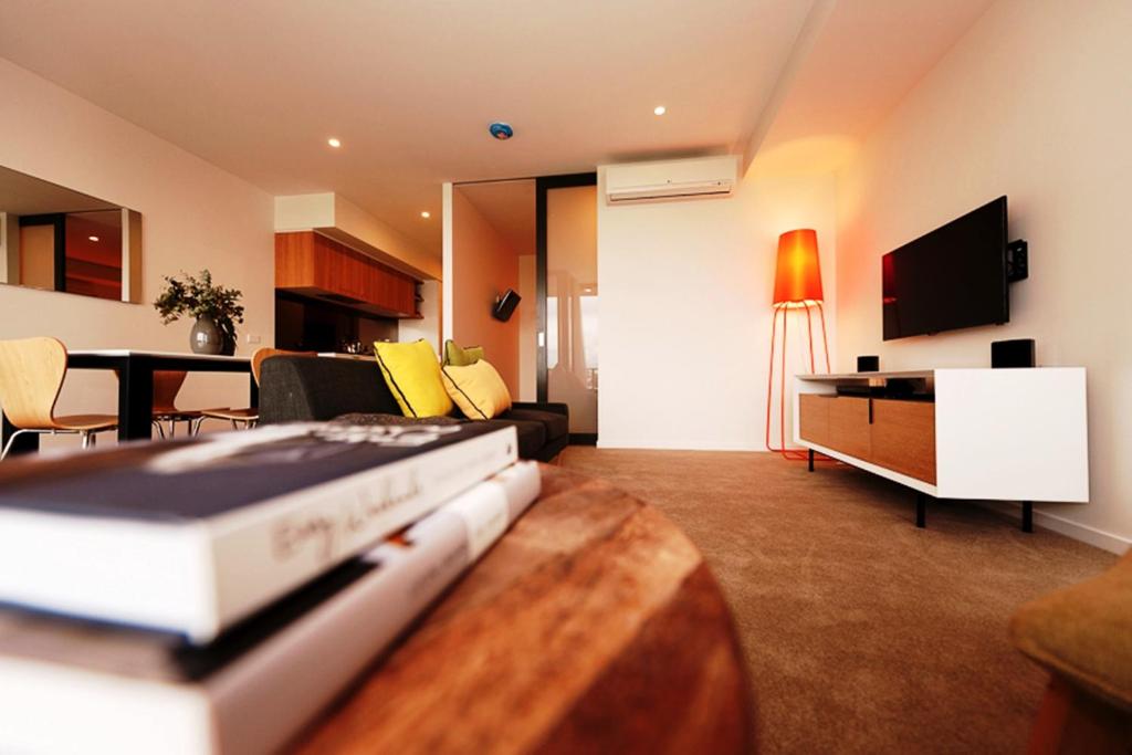 a living room with a couch and a table with a tv at Vine Apartments South Brisbane in Brisbane