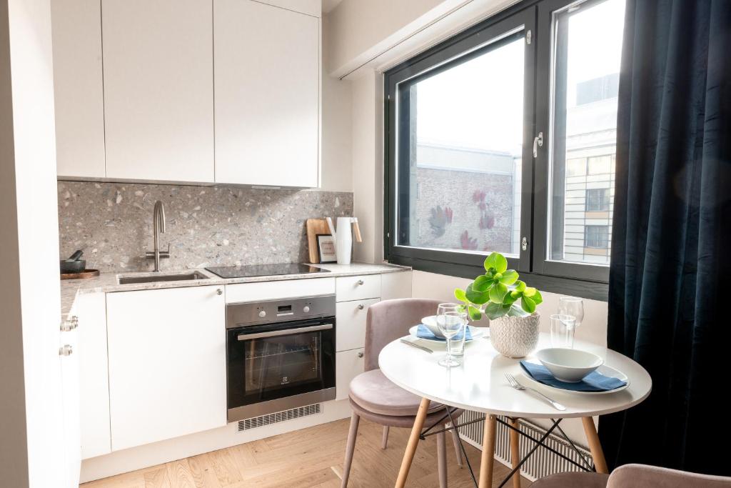 a white kitchen with a table and a window at 2ndhomes Cozy high-quality Studio in Kluuvi with Balcony in Helsinki