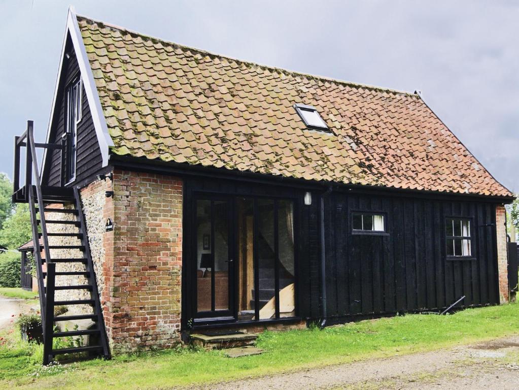 a small black house with a staircase in front of it at The Granary - E3669 in Saxtead