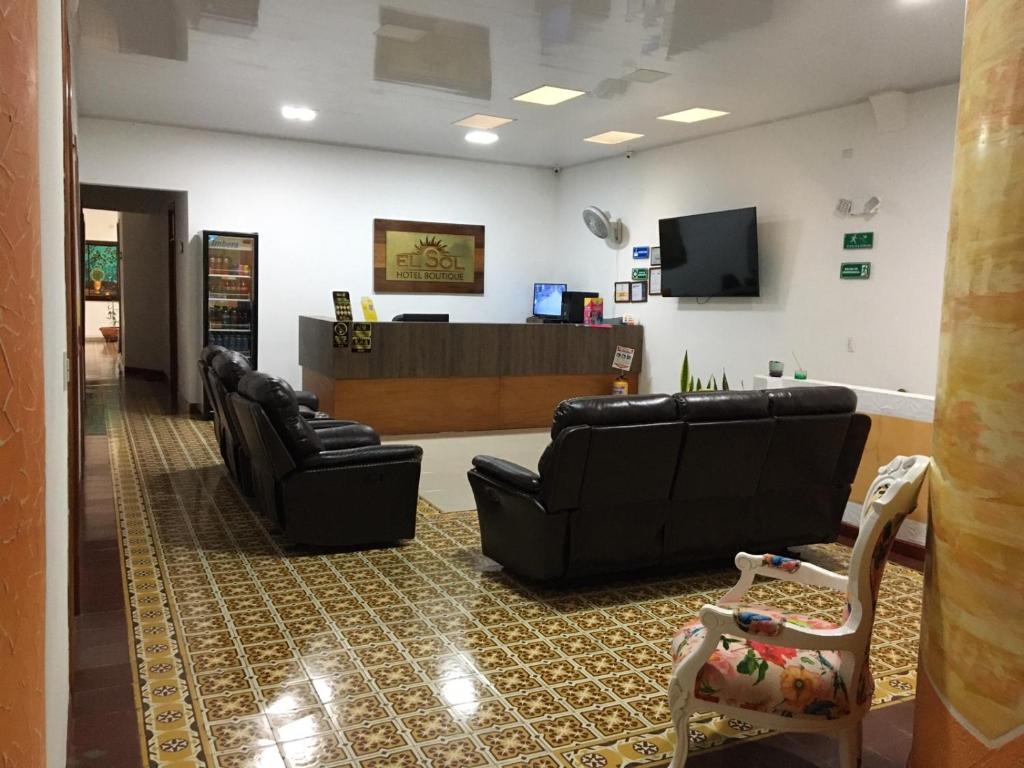 une salle d'attente avec canapés en cuir noir et caisse dans l'établissement Hotel Boutique el Sol, à Cartago