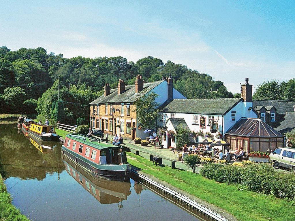 a boat is docked in a river next to buildings at Hollybush Cottage - E2800 in Cheddleton