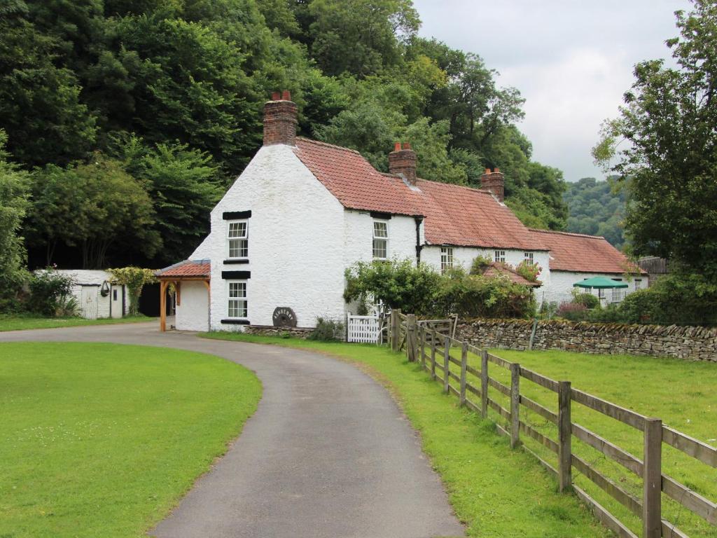 a white house with a fence next to a road at Ashberry Cottage in Rievaulx