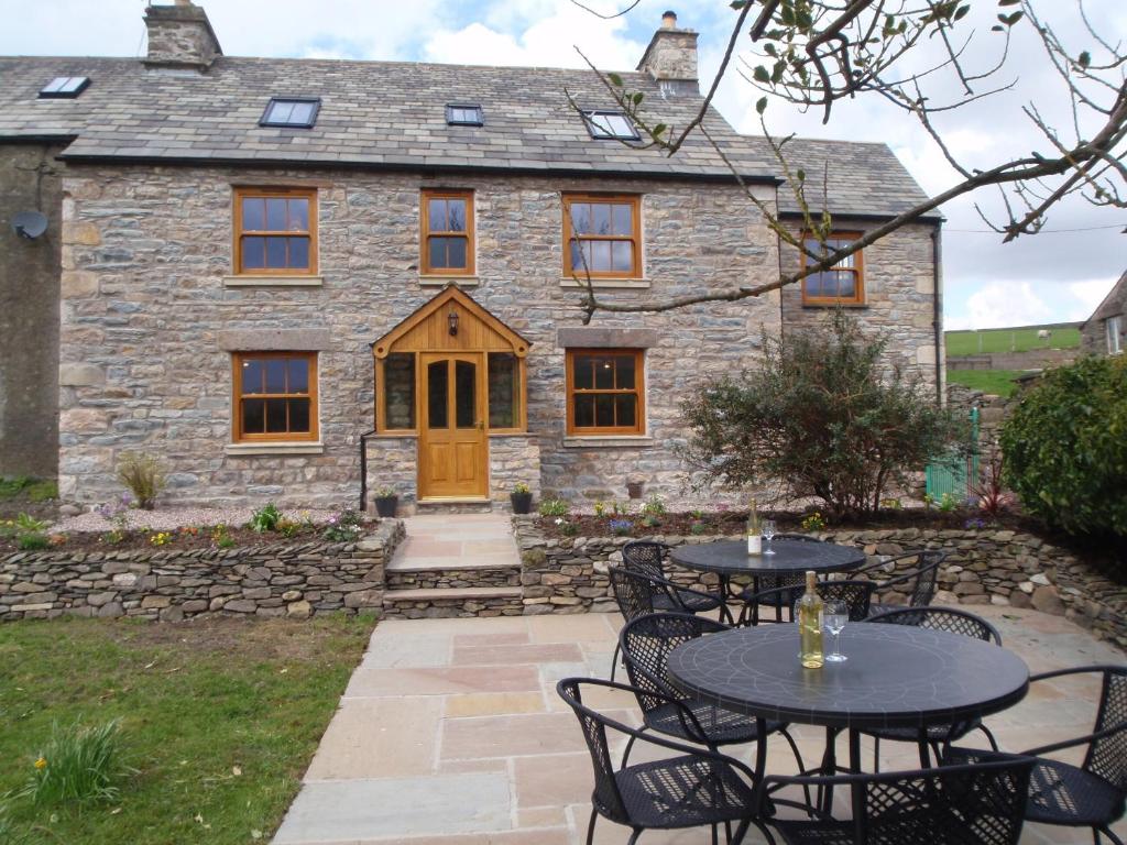 a stone house with tables and chairs in front of it at Gateside Farmhouse Sedbergh in Sedbergh