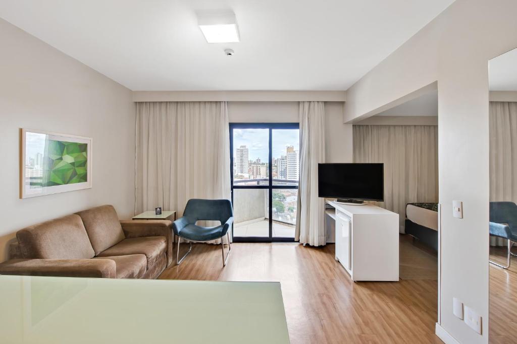 a living room with a couch and a tv at Blue Tree Garden Bauru in Bauru