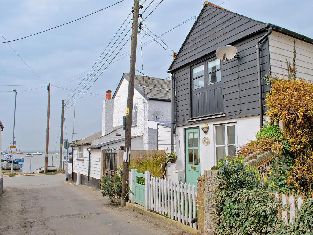 ein schwarzweißes Haus mit einem weißen Zaun in der Unterkunft Stoker Loft in West Mersea