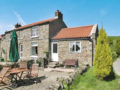 a stone house with a table and chairs and a patio at The Cottage in Cloughton