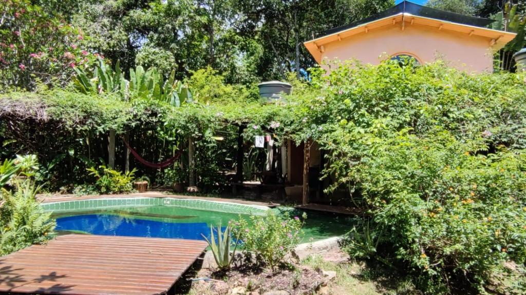 a swimming pool in a garden with a wooden deck at Chalés Manhana- Água in Alto Paraíso de Goiás
