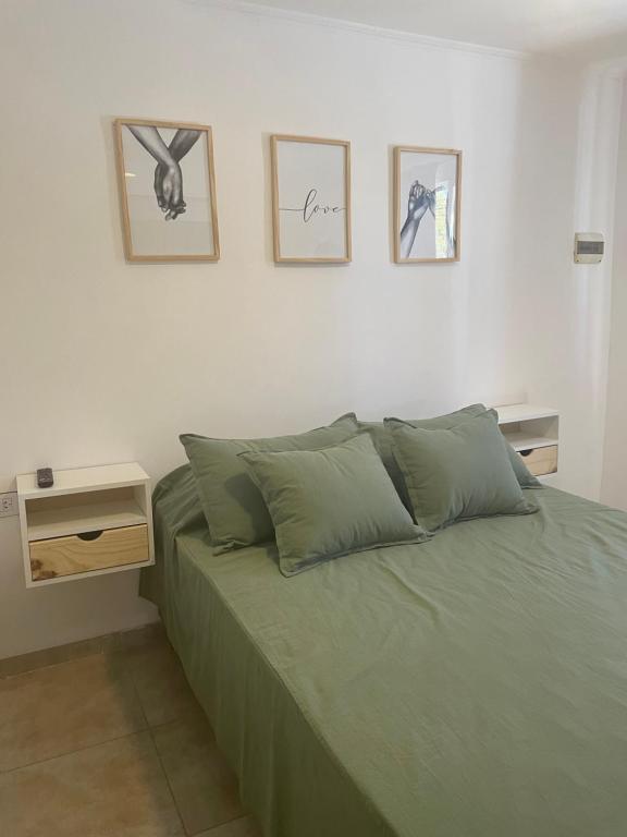 1 dormitorio con cama verde y cuadros en la pared en Departamento céntrico Colón en Colón
