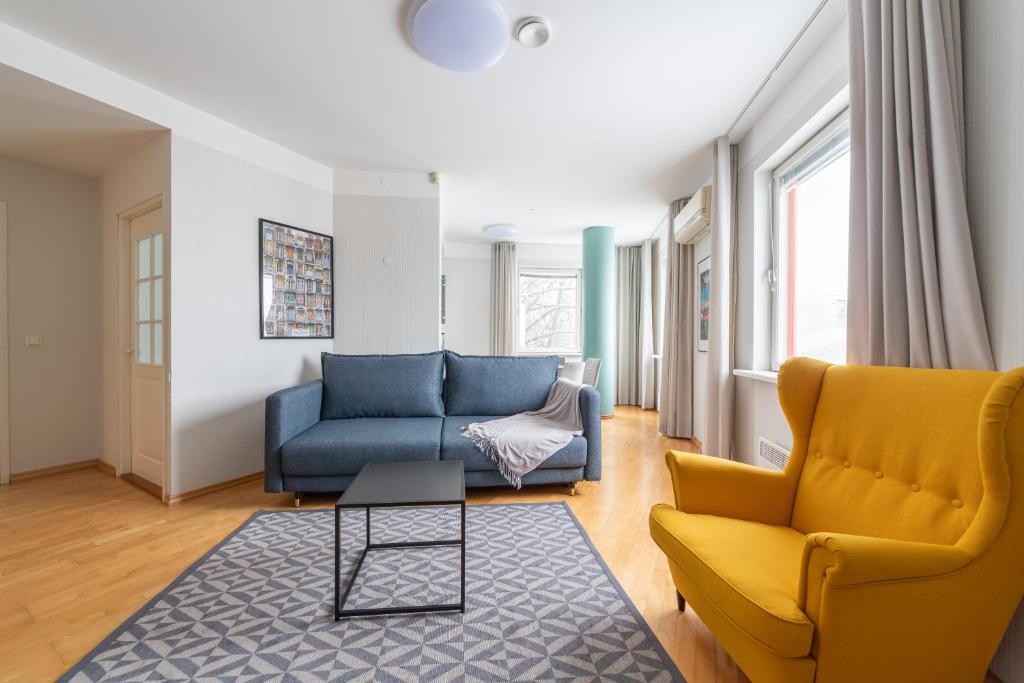 a living room with a blue couch and yellow chairs at Old Town - Passaaz Apartment in Tallinn