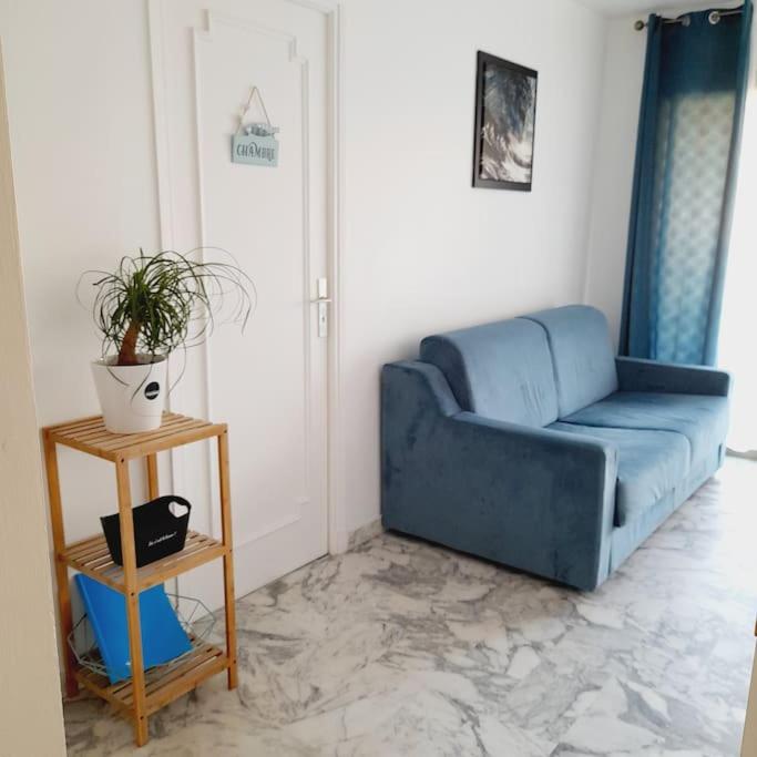un canapé bleu dans un salon avec une table dans l'établissement Appartement proche croisette avec parking et climatisation, à Cannes