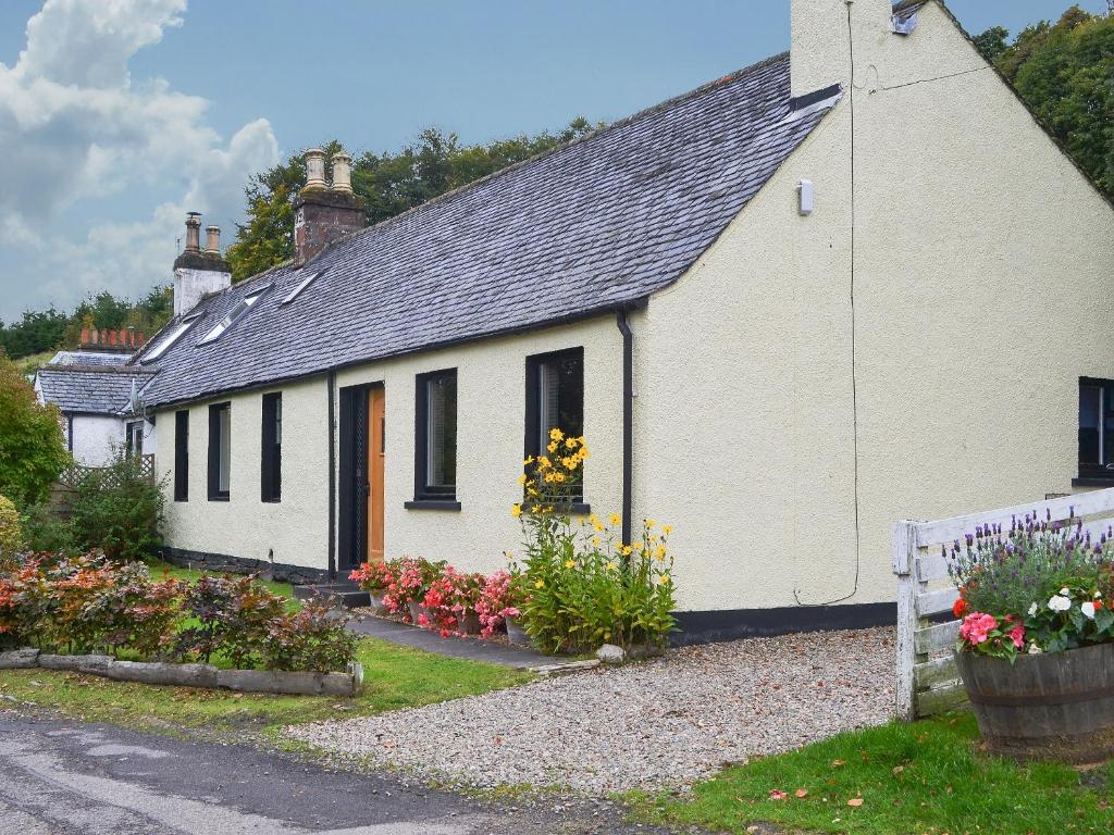 een wit huis met bloemen ervoor bij Kinnettas Cottage in Strathpeffer