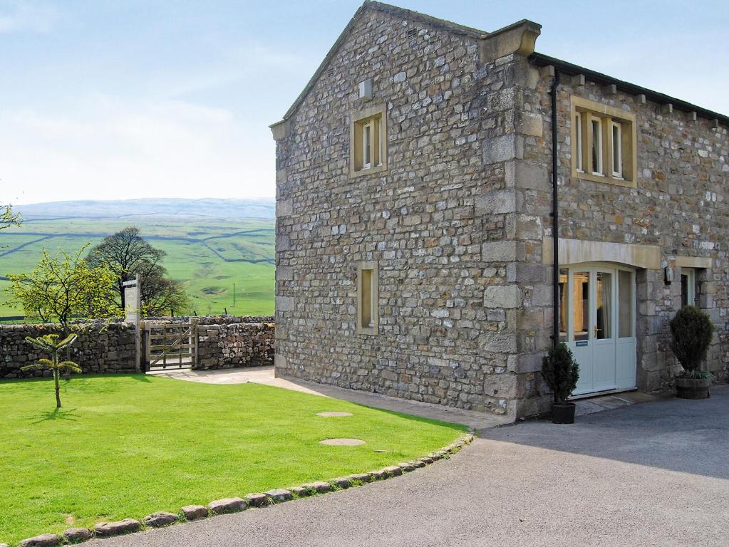 a stone house with a green lawn in front of it at Halton Gill Cottage in Deepdale