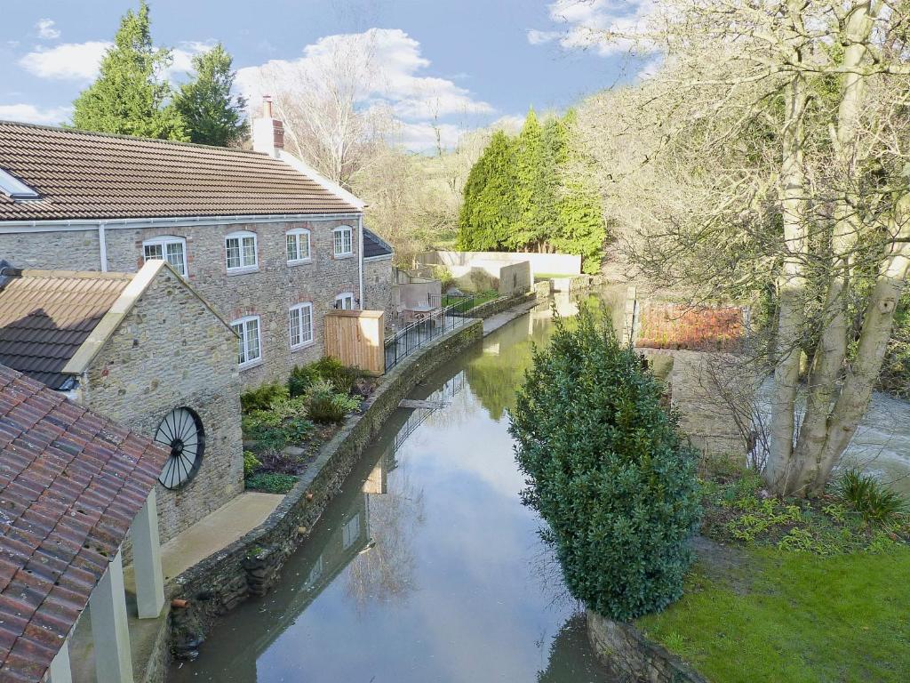 a river in the middle of a city with buildings at Dippers Folly in Buckland Dinham