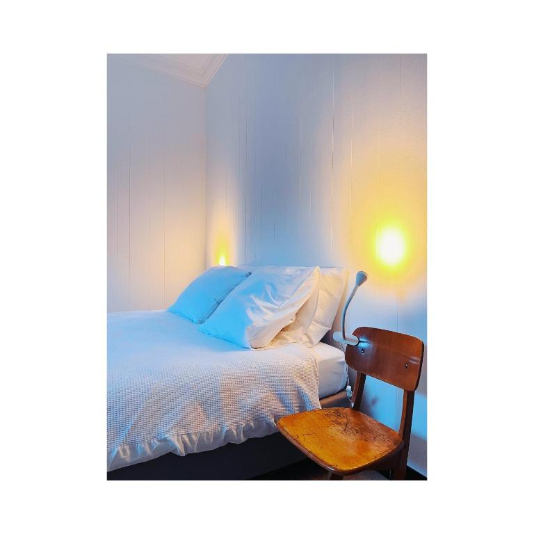 Lo-ReningeにあるIn nduukのベッドルーム(白いベッド1台、木製の椅子付)