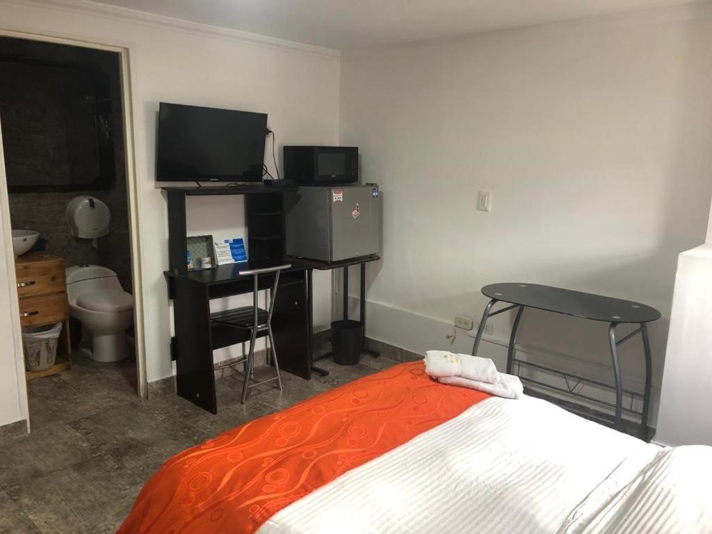 een slaapkamer met een bed, een bureau en een televisie bij Hotel Fénix Real Bogotá in Bogota