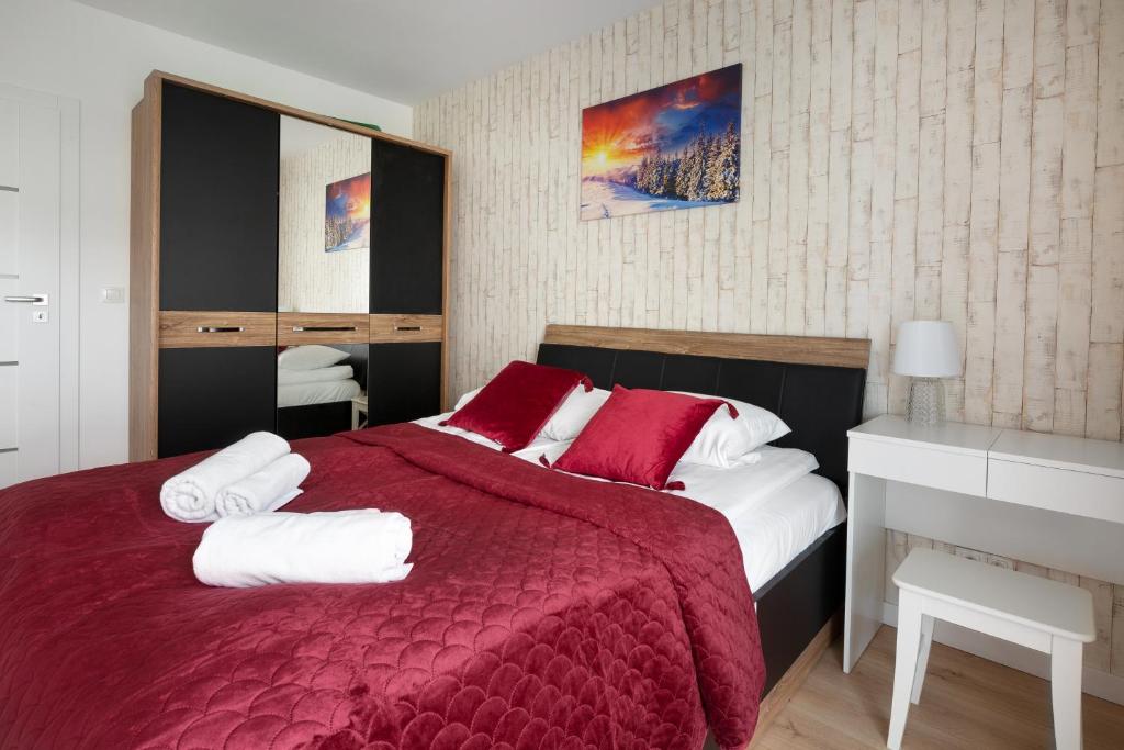 ein Schlafzimmer mit einem roten Bett mit Handtüchern darauf in der Unterkunft Apartament SUNRISE Kudowa z balkonem in Kudowa-Zdrój