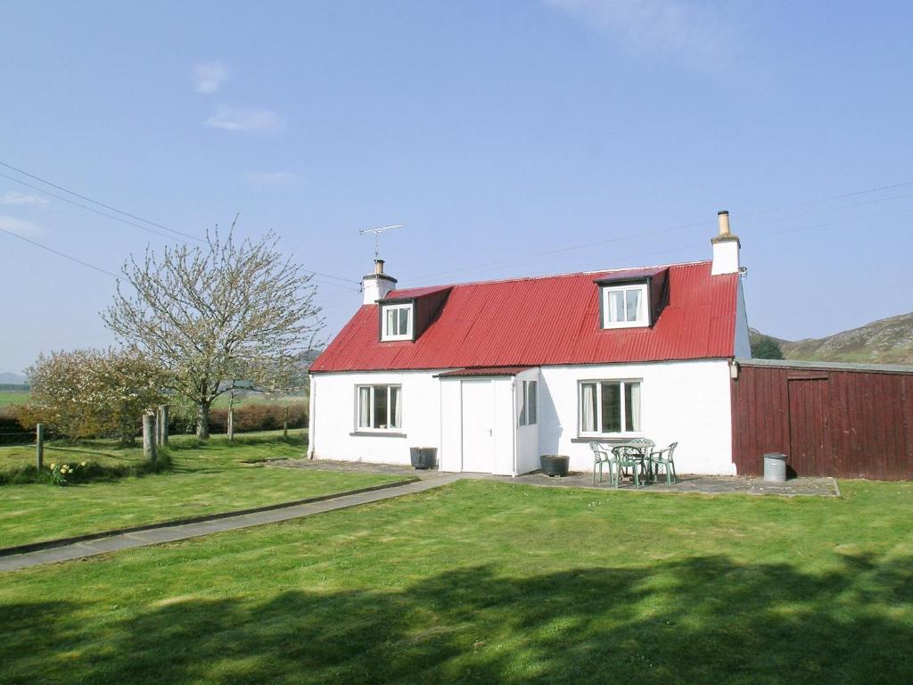 a white house with a red roof and a table at Wester Croachy Cottage in Aberarder