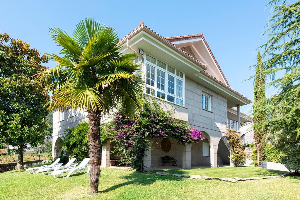 una palmera frente a una casa con tumbonas en Villa Campo Das Medas , en medio de la naturaleza con piscina privada de sal, en Gondomar