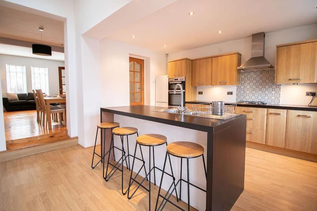a kitchen with a island with bar stools at Burnaby's home, by Home Host, free on street parking in Cardiff