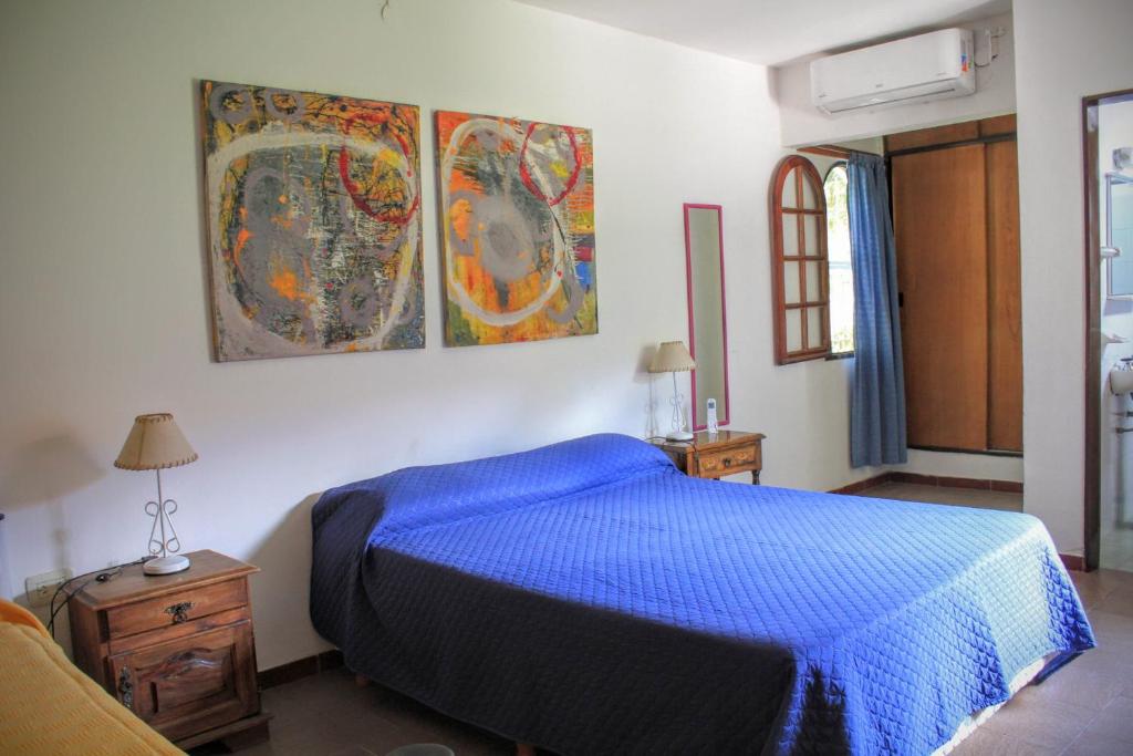 a bedroom with a blue bed and paintings on the wall at flia Fortuna2 in Mina Clavero