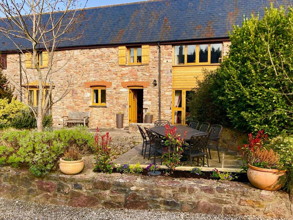 uma casa com uma mesa e cadeiras num jardim em Barn Owl em Ipplepen