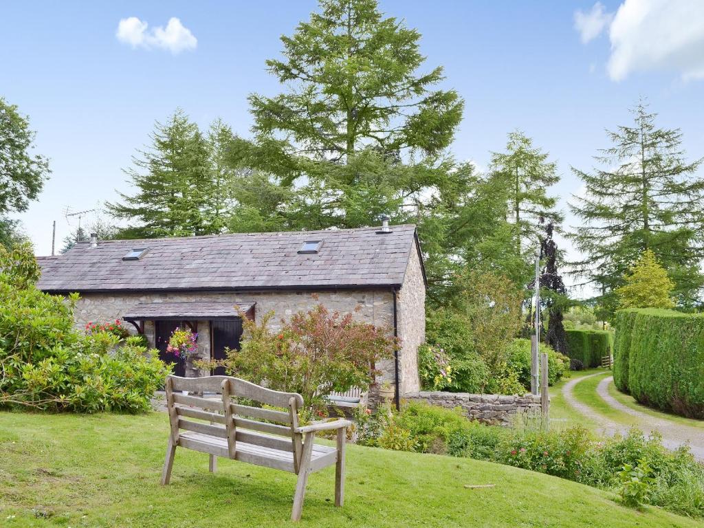 a bench sitting in the grass in front of a building at Honeysuckle Cottage in Nerquis