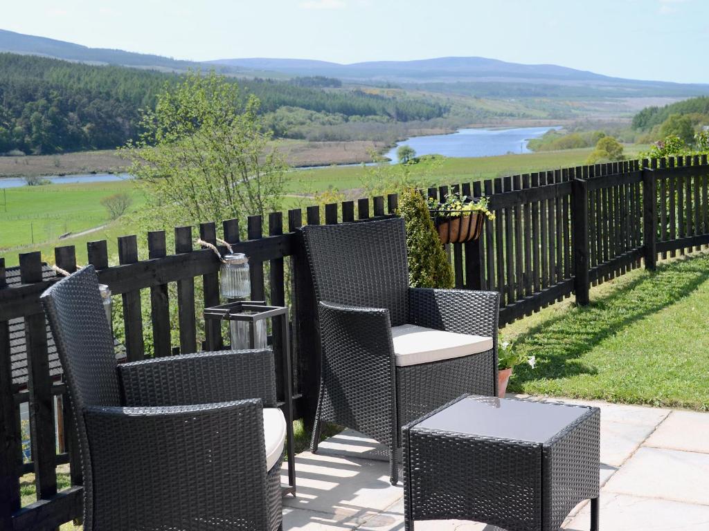 a patio with chairs and tables and a view of a river at The Wee Hoose in Achnahanat