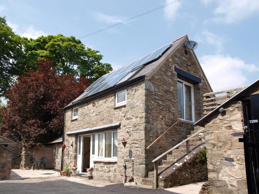 une ancienne maison en pierre avec un toit solaire dans l'établissement The Coach House - Hw7782, à Llanarmon Dyffryn-Ceiriog