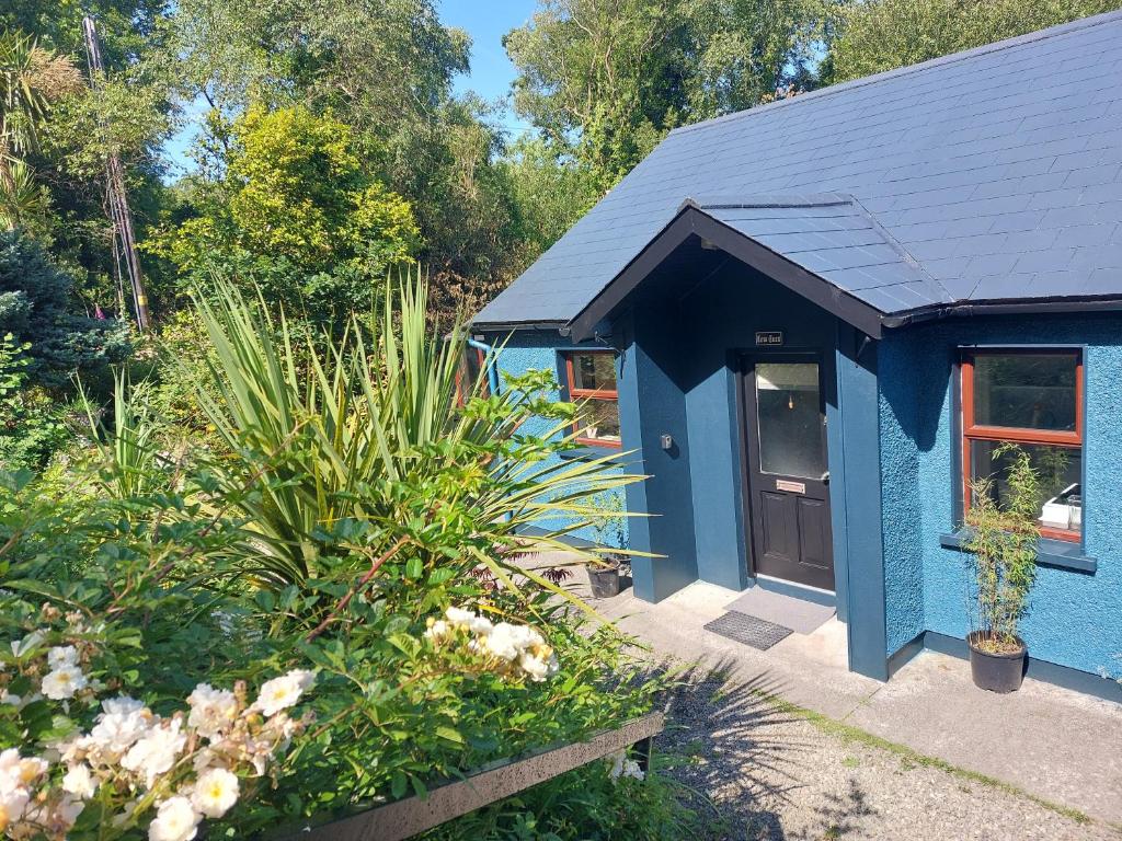 a blue building with a door in a garden at Harbourside House Glengarriff in Glengarriff