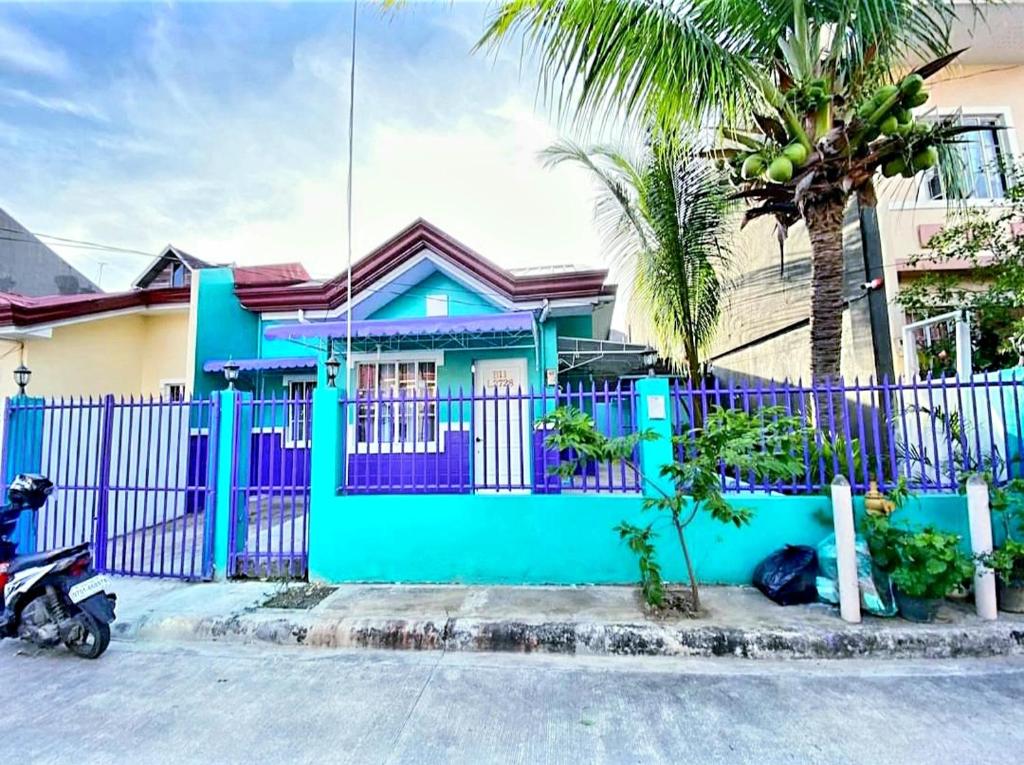 a blue fence in front of a house with a palm tree at Kalai's Rental Dwellings (KRD) in Cotcot