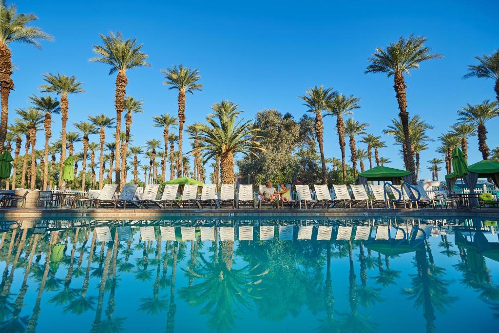 una piscina con palmeras y sillas en Palm Springs Camping Resort Loft Cabin 1, en Palm Desert