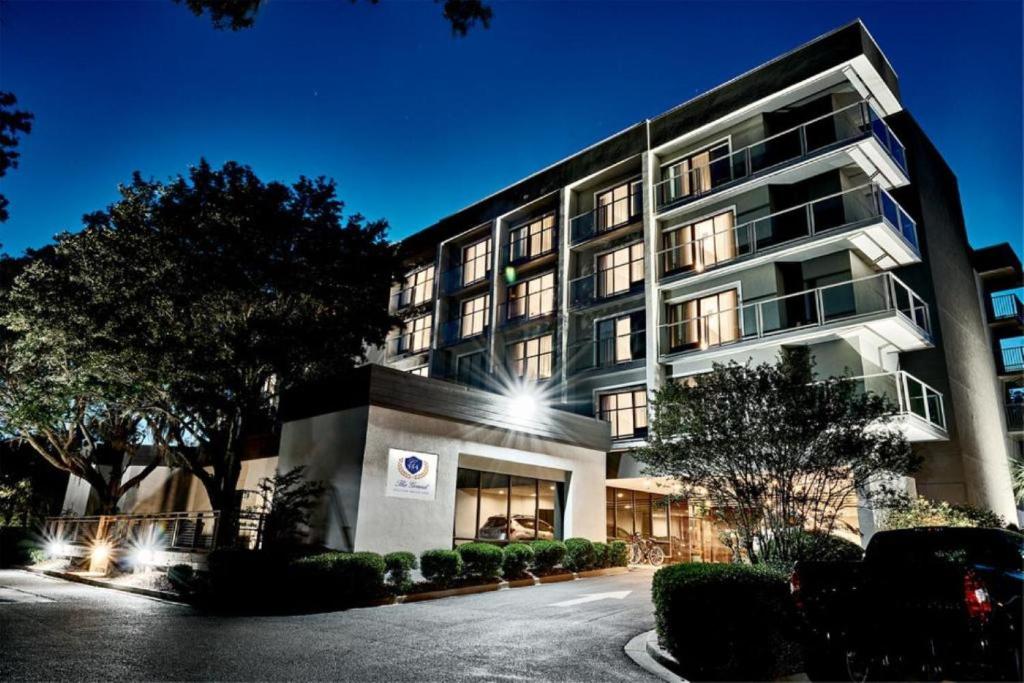 Grand Hilton Head Inn, Ascend Hotel Collection في جزيرة هيلتون هيد: مبنى كبير فيه سيارة متوقفة أمامه