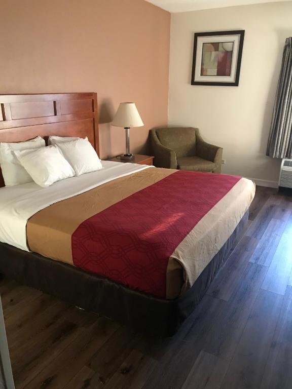 um quarto de hotel com uma cama grande e uma cadeira em The Best Inn & Suites em Markham