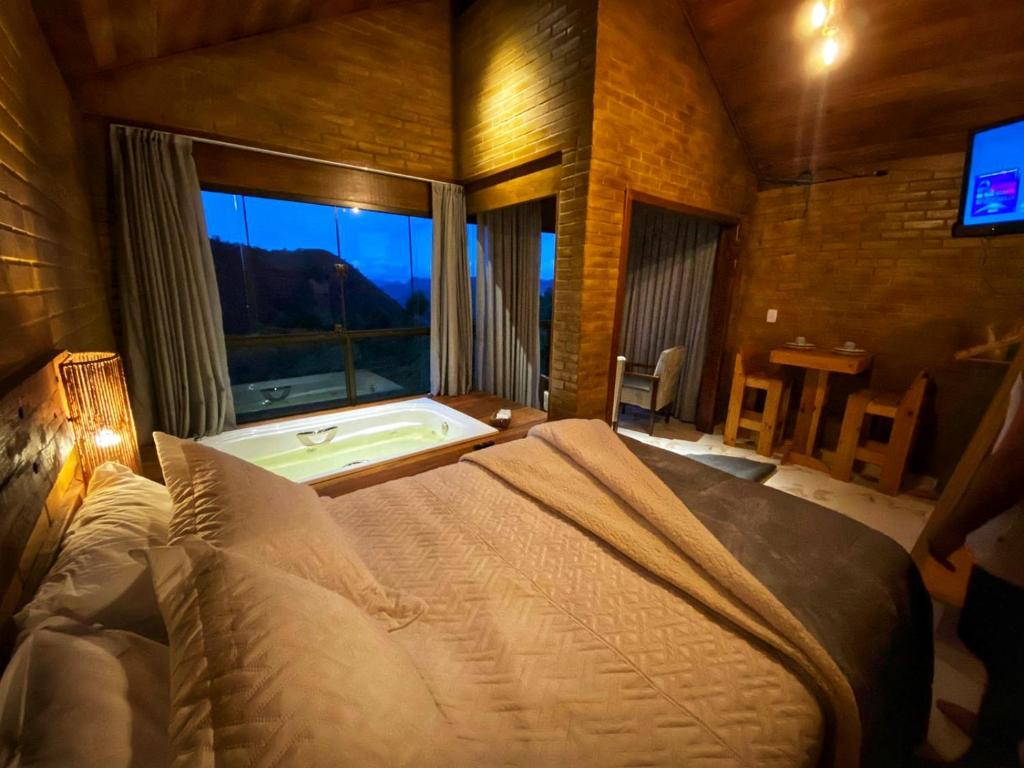 a bedroom with a bed and a tub and a window at Vila Italliana Chalés - Chalé Milão in Santa Teresa