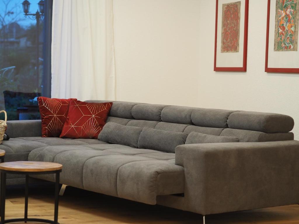 un sofá gris en una sala de estar con mesa en foxxbau - urlaubswohnen im Saarschleifenland, en Merzig