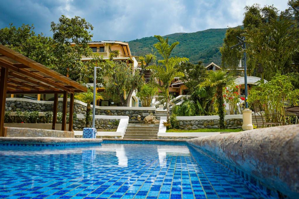 une piscine dans un complexe avec des montagnes en arrière-plan dans l'établissement Uzhupud Garden Hotel & Lodge, à Paute