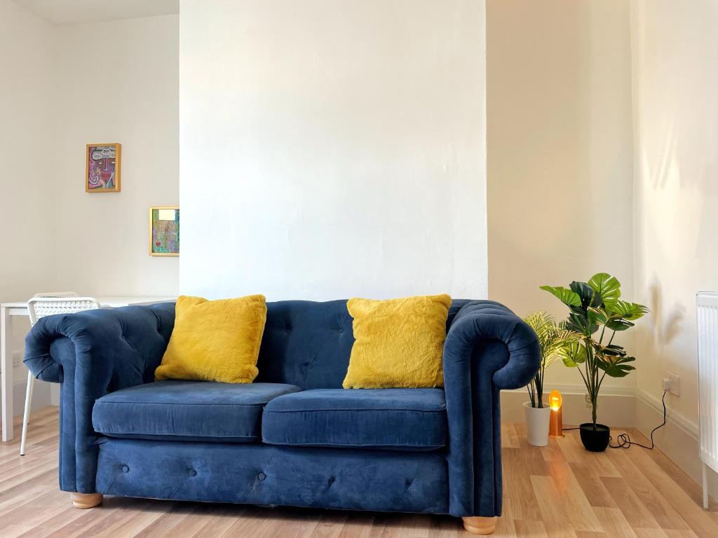 a blue couch in a living room with yellow pillows at 2 Bed Gem Margate, Free Parking in Kent