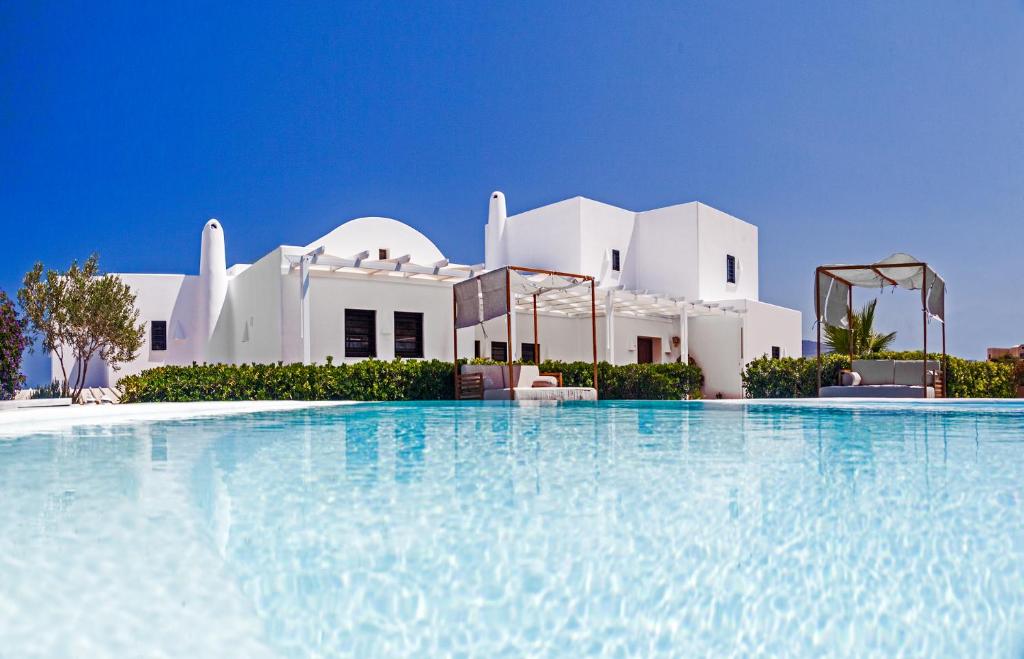 a large swimming pool in front of a white house at Villa Irene Santorini in Vourvoulos