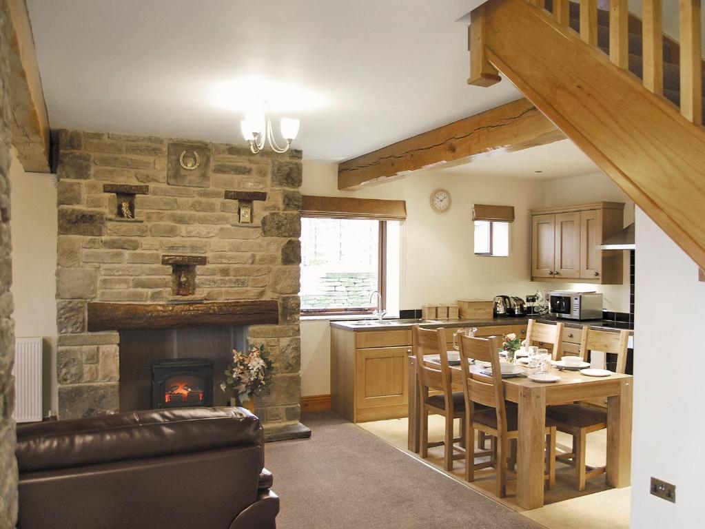 a kitchen and dining room with a stone fireplace at Hutter Hill Barn West in Silsden