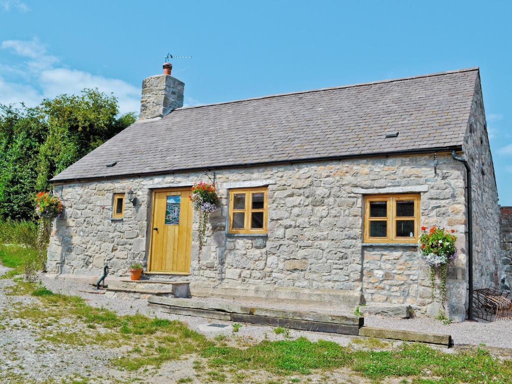 a stone cottage with a yellow door and windows at Tre Fardre in Kinmel