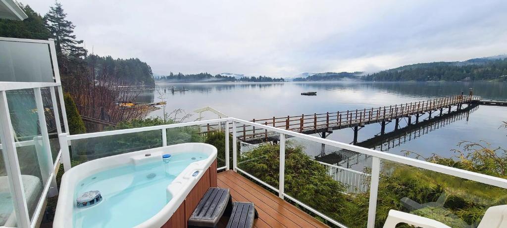 a bath tub on a balcony with a view of a dock at Seascape Beach House by IRIS PROPERTIES! in Sooke