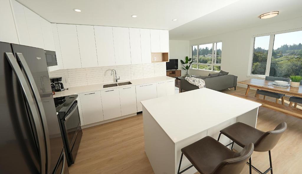 a kitchen with white cabinets and a white table and chairs at The Belmont by IRIS PROPERTIES! in Victoria