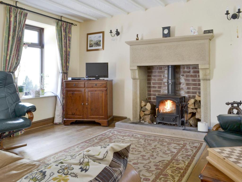 a living room with a fireplace and a tv at Poppy Cottage in Bonsall