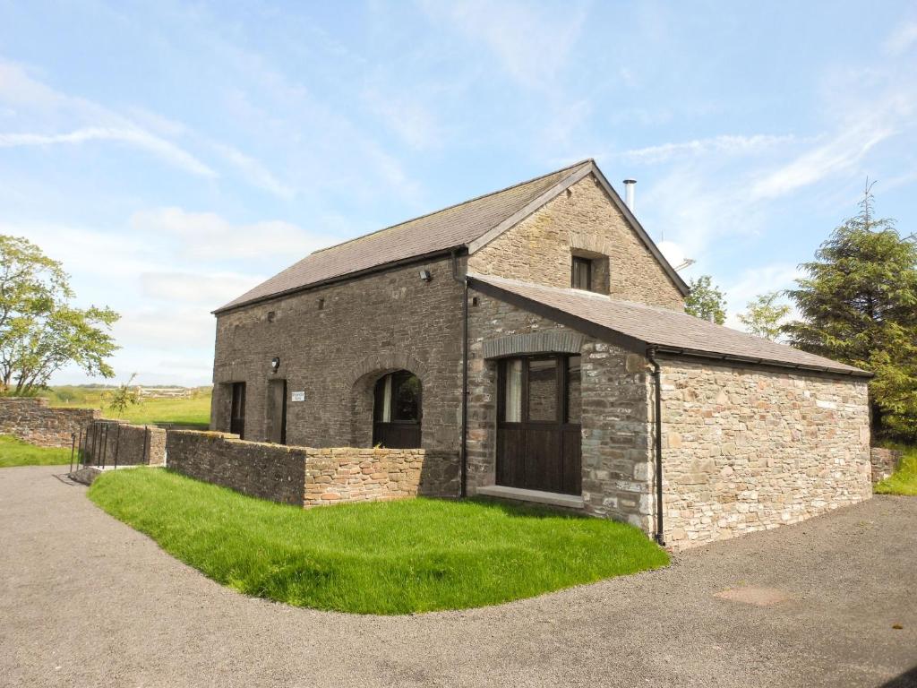 an old brick building with a grassy yard at Rhandir Barn in Ffair-fâch