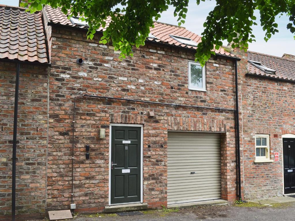 a brick house with a garage and a door at Biggan Mews in York