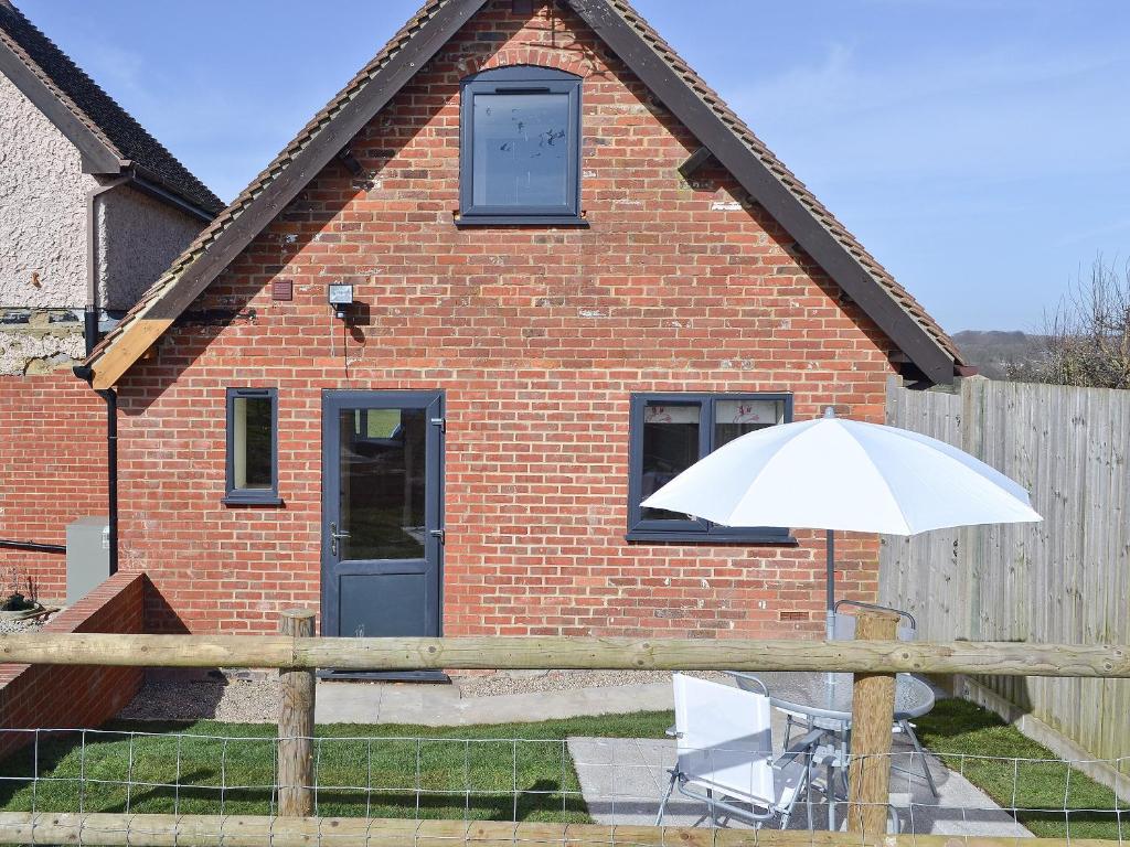 a white umbrella and a chair in front of a brick house at A Bit On The Side in Chillenden
